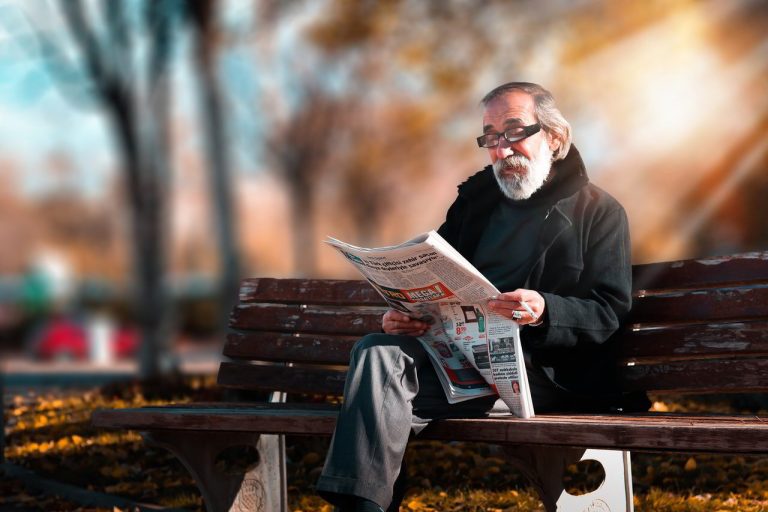 Man reading the paper on park bench